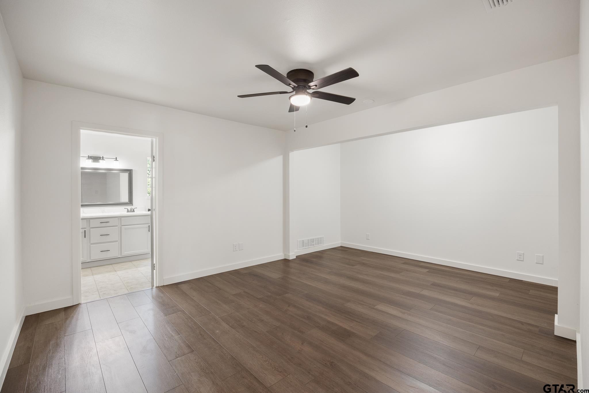 1538 North Hill Road Tyler, TX 75702 - Photo 23 of 29 an empty room with wooden floor a ceiling fan and windows