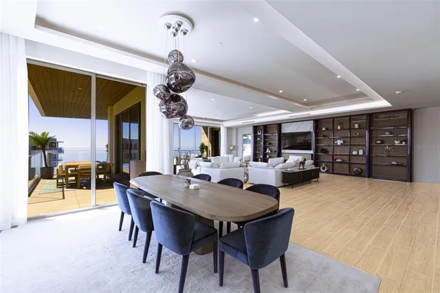 a kitchen with stainless steel appliances granite countertop a stove a refrigerator a kitchen island a dining table and chairs with wooden floor