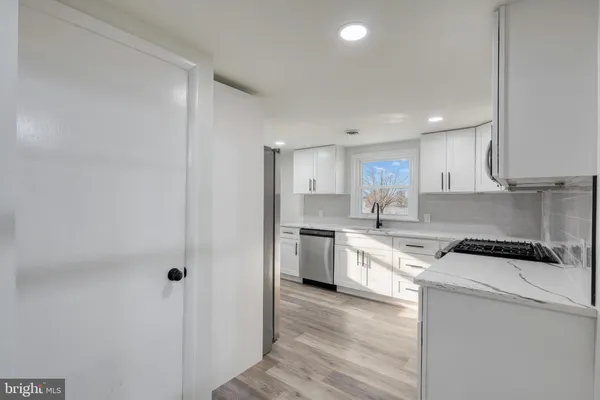 a kitchen with a sink stove cabinets and wooden floor