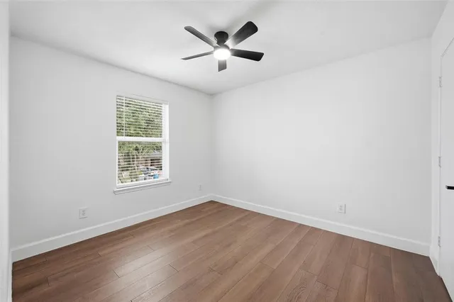 an empty room with wooden floor and ceiling fan