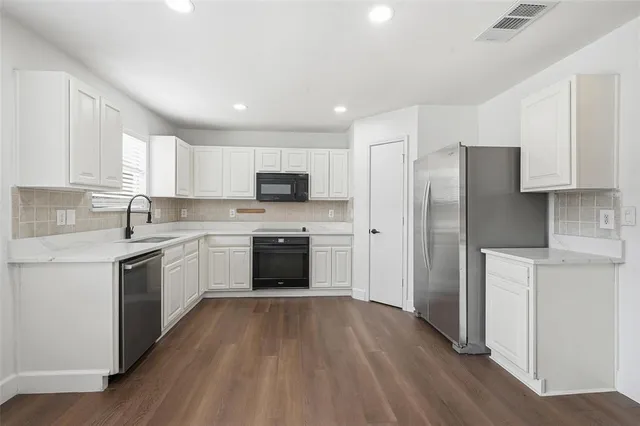 a kitchen with a white cabinets a sink a window and stainless steel appliances