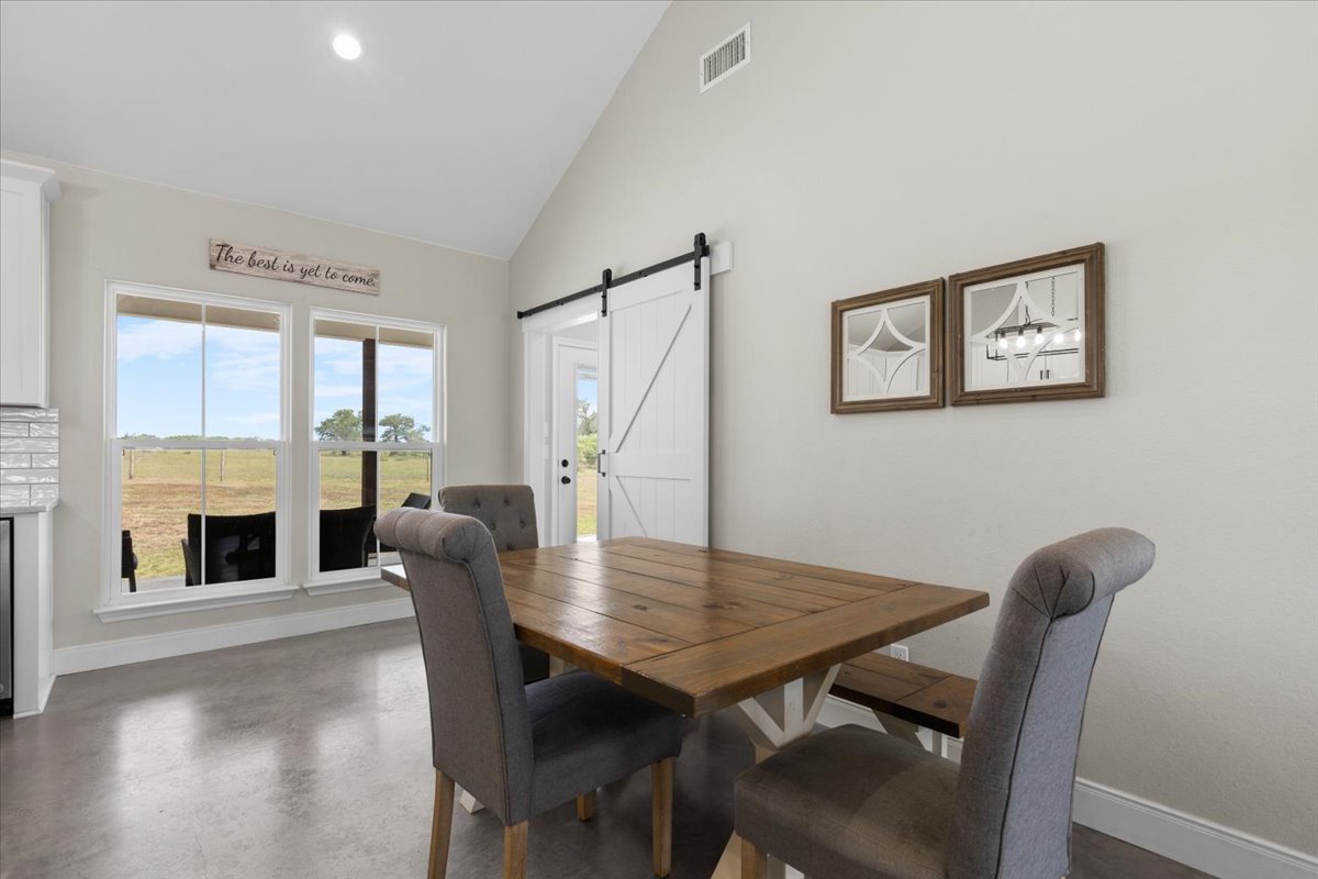 3389 Sparta Field Road Waelder, TX 78959 - Photo 10 of 40 Dining space with a barn door, concrete flooring, high vaulted ceiling, and recessed lighting