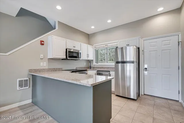 a kitchen with stainless steel appliances granite countertop a refrigerator a sink dishwasher a oven with white cabinets and wooden floor