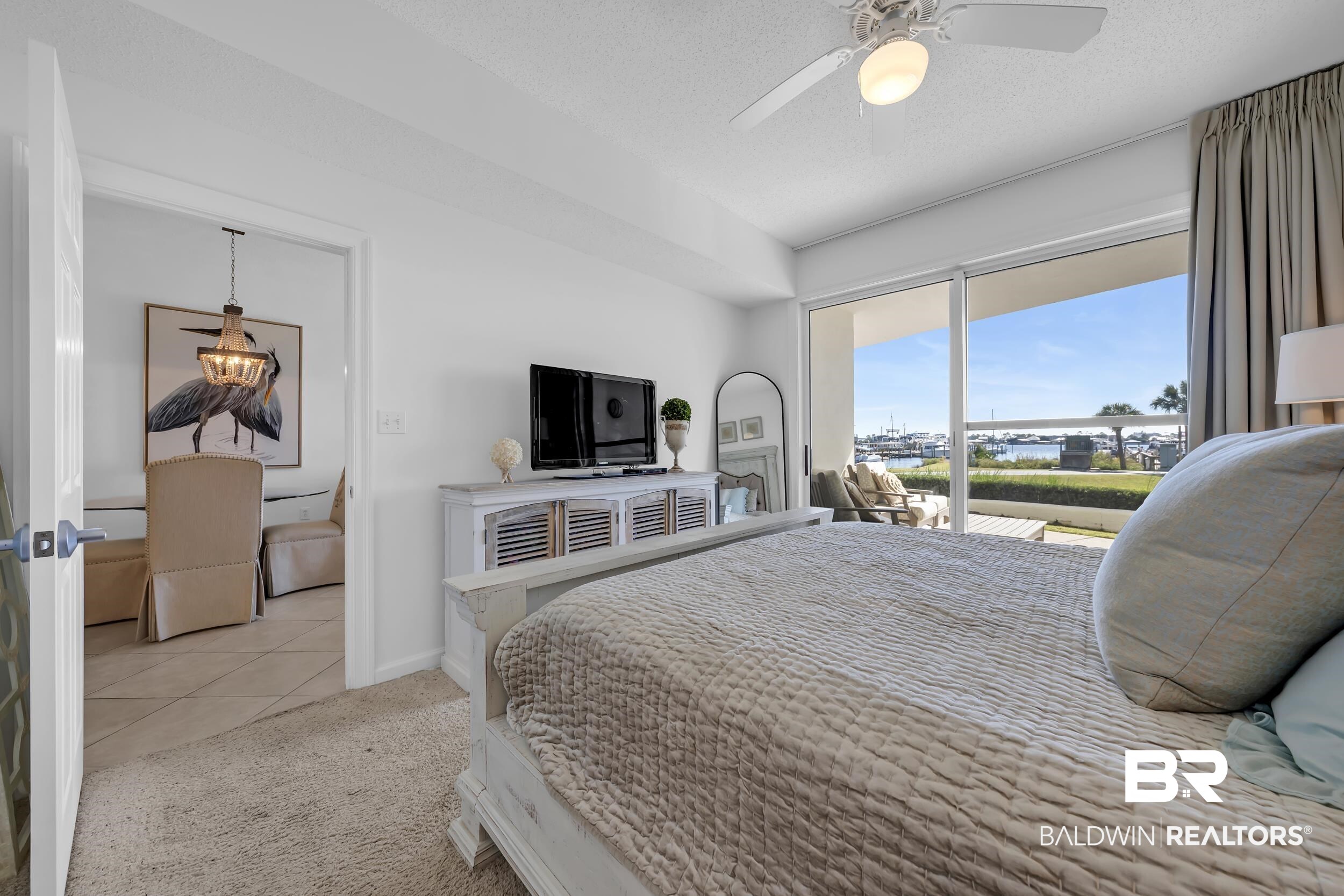 27282 Canal Road, Unit 104 Orange Beach, AL 36561 - Photo 34 of 79 Bedroom featuring a textured ceiling, light colored carpet, access to outside, light tile patterned floors, and ceiling fan