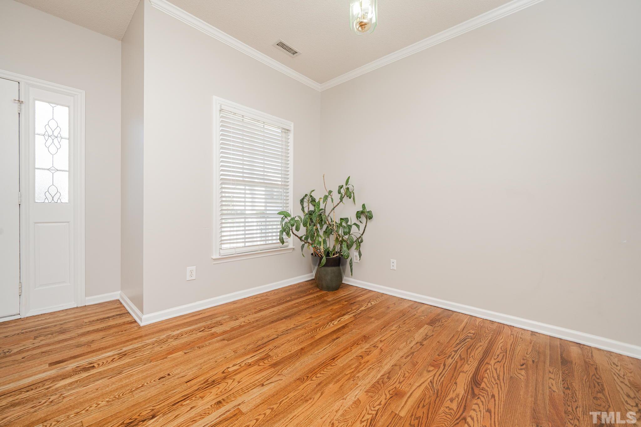 114 Calebra Way Cary, NC 27519 - Photo 7 of 50 a view of an empty room with wooden floor and a window