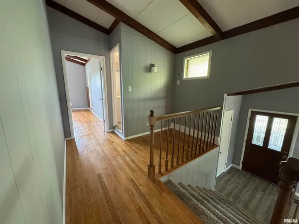 a view of a hallway with wooden floor and stairs