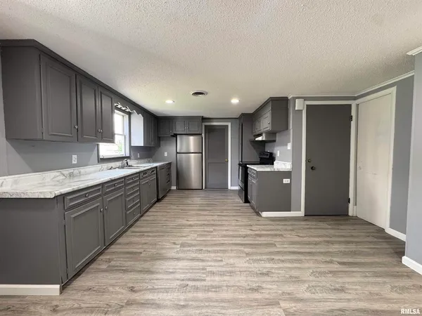 a large kitchen with stainless steel appliances granite countertop a refrigerator and a sink