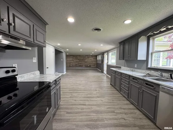 a large kitchen with stainless steel appliances a large counter top a stove and a sink