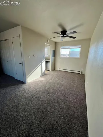 a view of a livingroom with a ceiling fan & windows