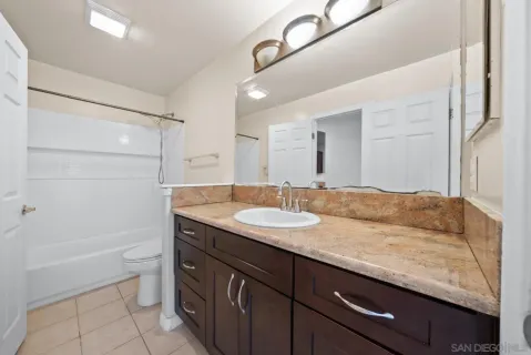 a bathroom with a granite countertop sink a toilet and shower