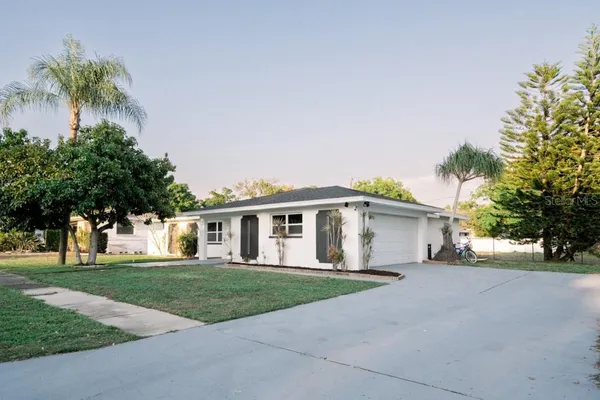 a view of house with a big yard and palm trees