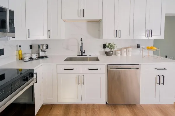 a kitchen with stainless steel appliances a white refrigerator a sink a stove a dining table and chairs