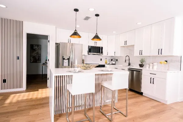 a kitchen with a sink a stove a refrigerator and white cabinets