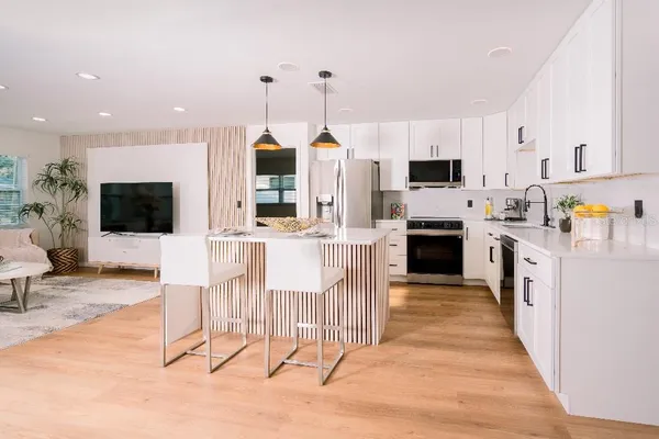 a kitchen with stainless steel appliances kitchen island granite countertop a stove top oven a sink a dining table and chairs