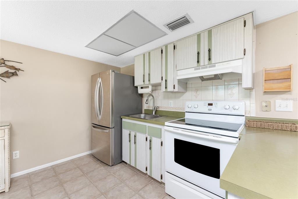 5055 North Beach Road, Unit 208 Englewood, FL 34223 - Photo 15 of 43 a kitchen with white cabinets and stainless steel appliances
