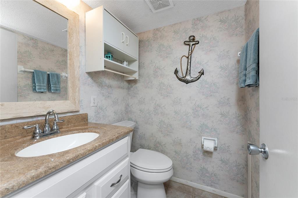 5055 North Beach Road, Unit 208 Englewood, FL 34223 - Photo 23 of 43 a bathroom with a granite countertop sink a toilet and mirror