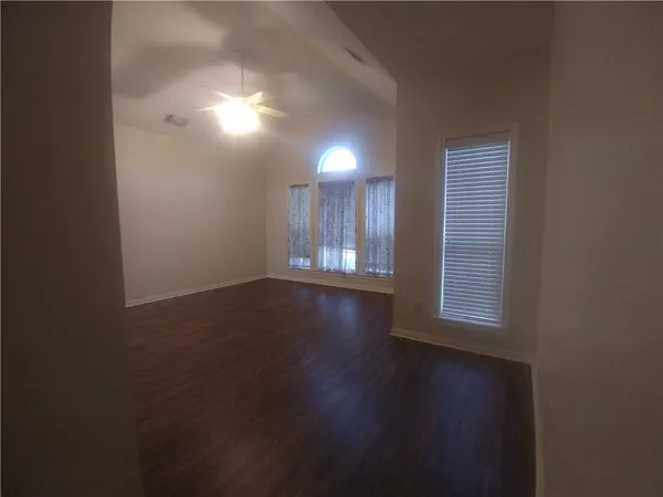 an empty room with wooden floor and windows