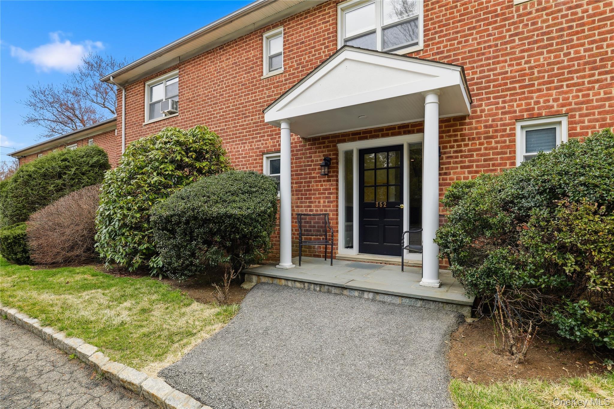 a view of a house with potted plants and a large tree