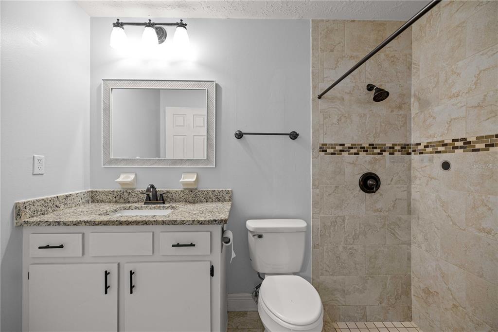 10500 Southwest 74th Court Ocala, FL 34476 - Photo 20 of 28 a bathroom with a granite countertop sink a toilet mirror and shower