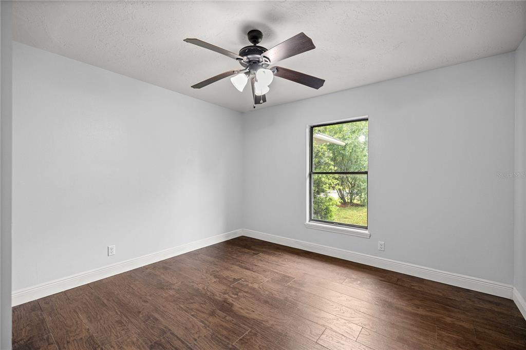 10500 Southwest 74th Court Ocala, FL 34476 - Photo 21 of 28 an empty room with wooden floor window and ceiling fan