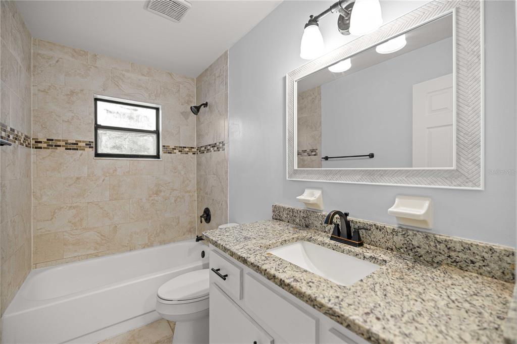 10500 Southwest 74th Court Ocala, FL 34476 - Photo 24 of 28 a bathroom with a granite countertop sink mirror toilet and bathtub