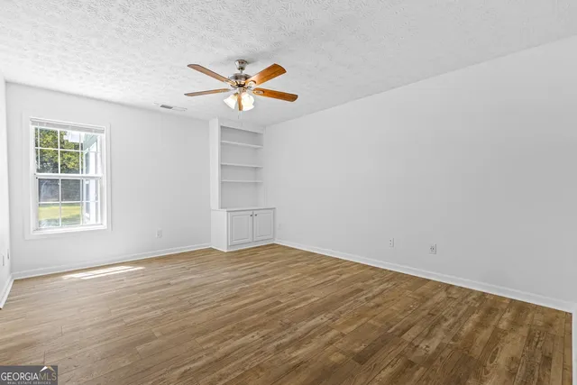 a view of an empty room with window and wooden floor