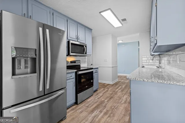 a kitchen with granite countertop a refrigerator stove and sink