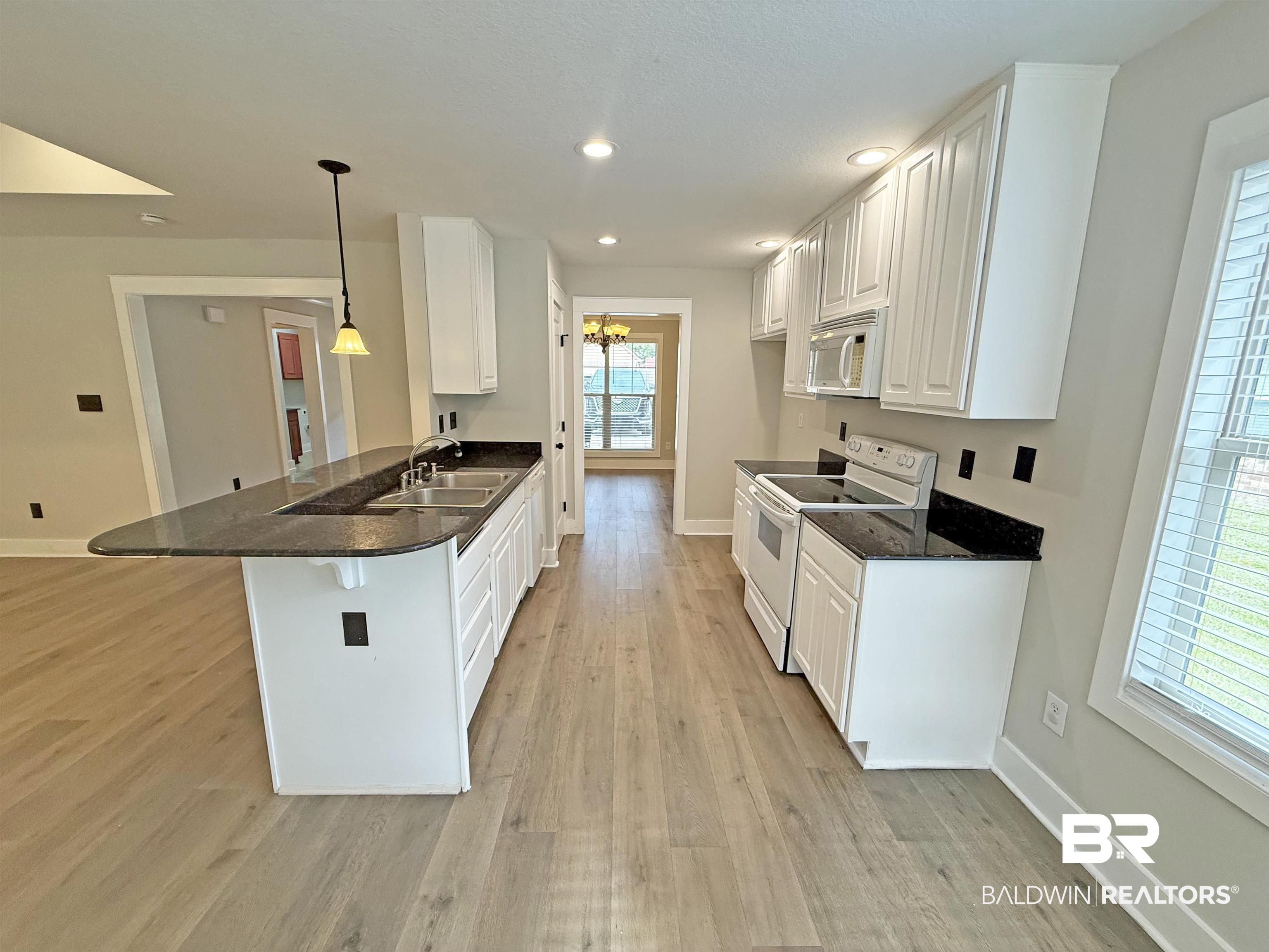 22023 Garland Loop Silverhill, AL 36576 - Photo 9 of 33 Kitchen with white appliances, a peninsula, light wood-style flooring, white cabinetry, and recessed lighting