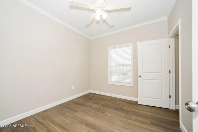 an empty room with wooden floor chandelier fan and windows