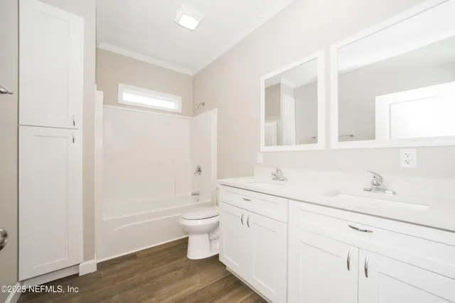 a bathroom with a double vanity sink a toilet and a shower