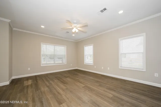 a view of an empty room with a window and wooden floor