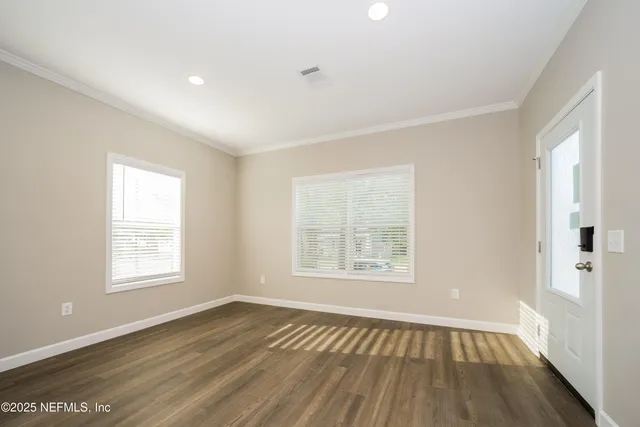 a view of an empty room with wooden floor and a window