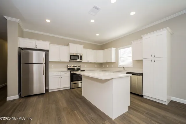 a kitchen with a refrigerator a stove top oven and white cabinets