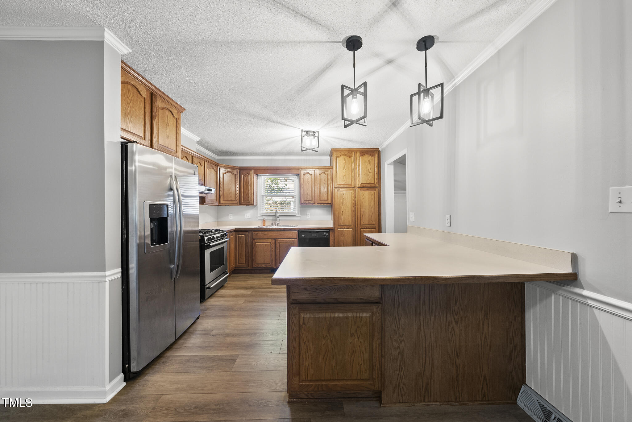 4500 Castlebar Drive Raleigh, NC 27604 - Photo 14 of 36 a kitchen with stainless steel appliances a table chairs in it and wooden floors
