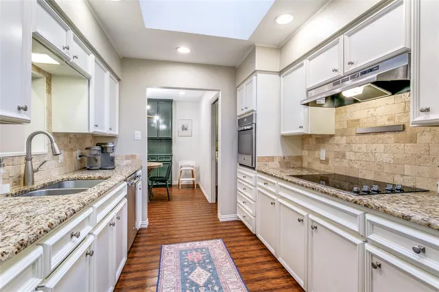 a kitchen with granite countertop a sink stove and cabinets