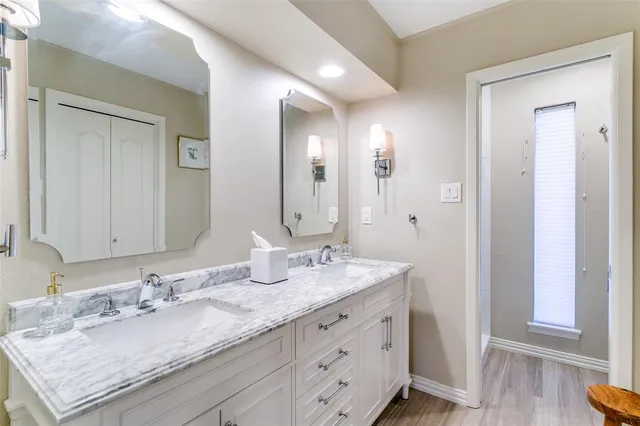 a bathroom with a granite countertop double vanity sink and a mirror