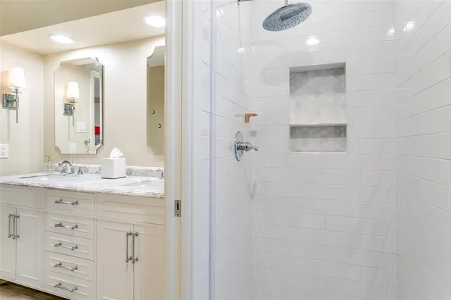 a bathroom with a granite countertop sink a mirror and a shower