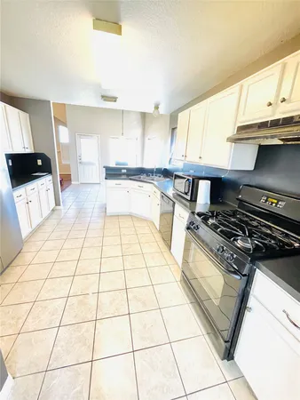 a kitchen with a stove a white cabinet and a view of living room
