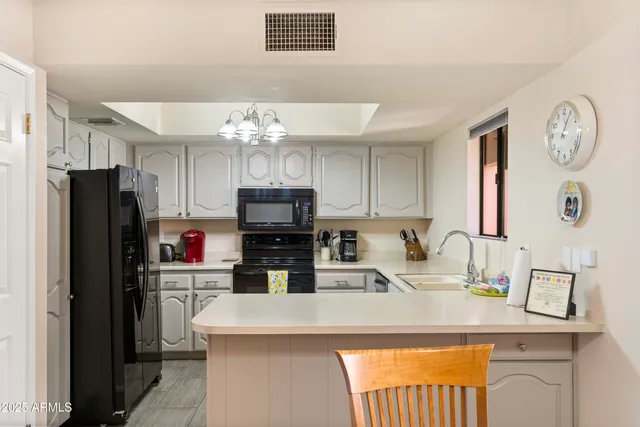 a kitchen with stainless steel appliances kitchen island granite countertop a refrigerator a stove top oven a sink dishwasher and white cabinets with wooden floor