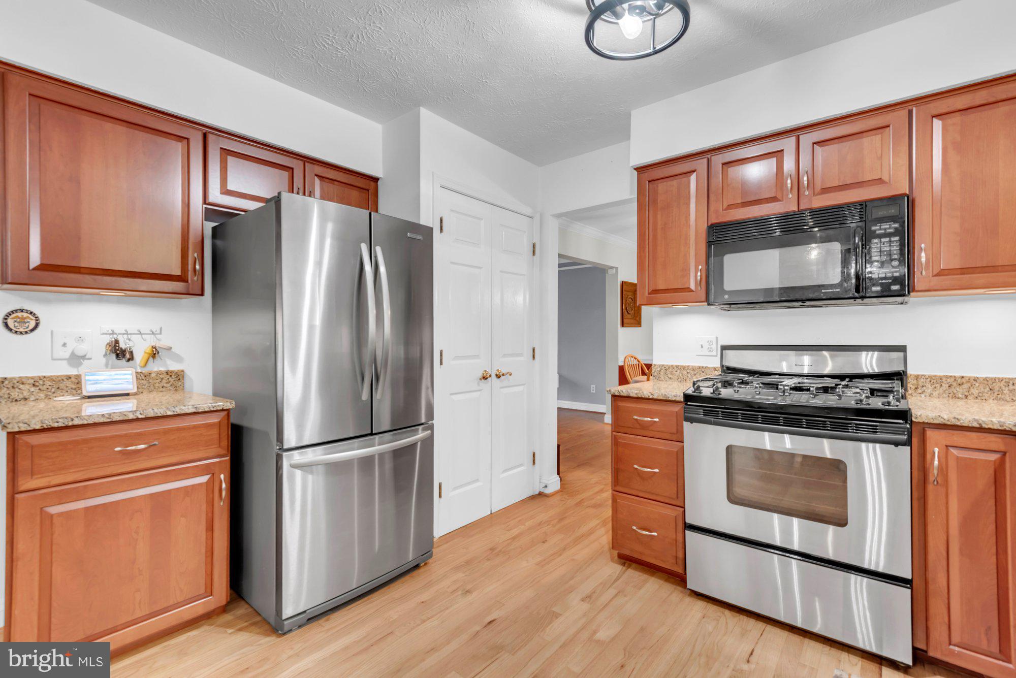 604 Academy Avenue Owings Mills, MD 21117 - Photo 4 of 51 a kitchen with granite countertop wooden floors wooden cabinets and stainless steel appliances