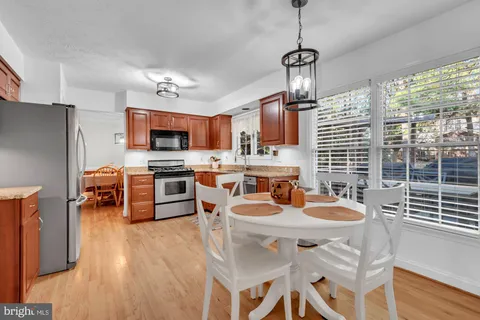 a kitchen with stainless steel appliances granite countertop a sink dishwasher a stove a refrigerator with a dining table and chairs