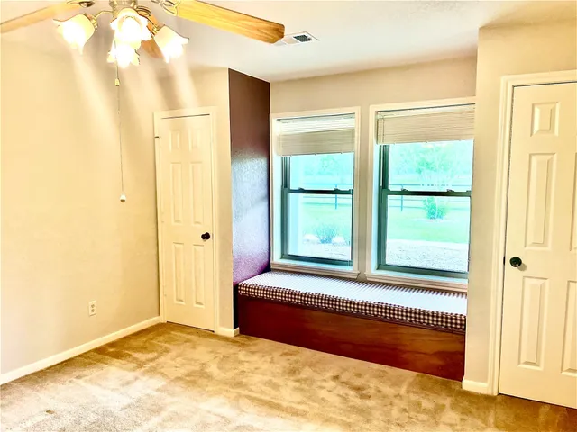 an empty room with closet and a ceiling fan