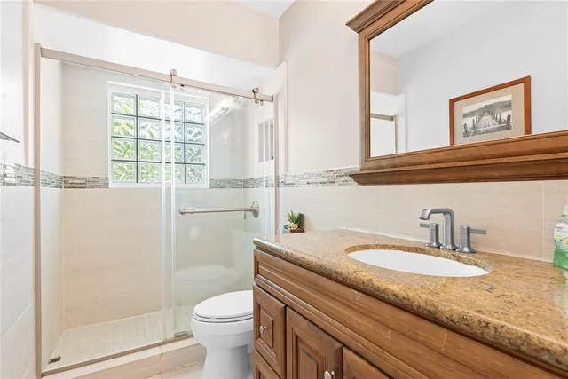 a bathroom with a granite countertop sink toilet and shower