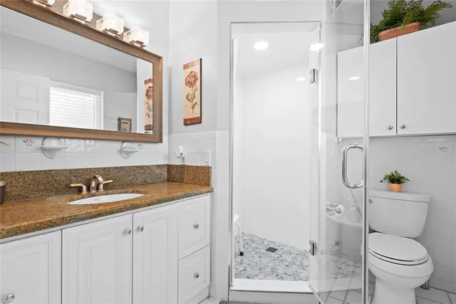 a bathroom with a granite countertop sink toilet and shower