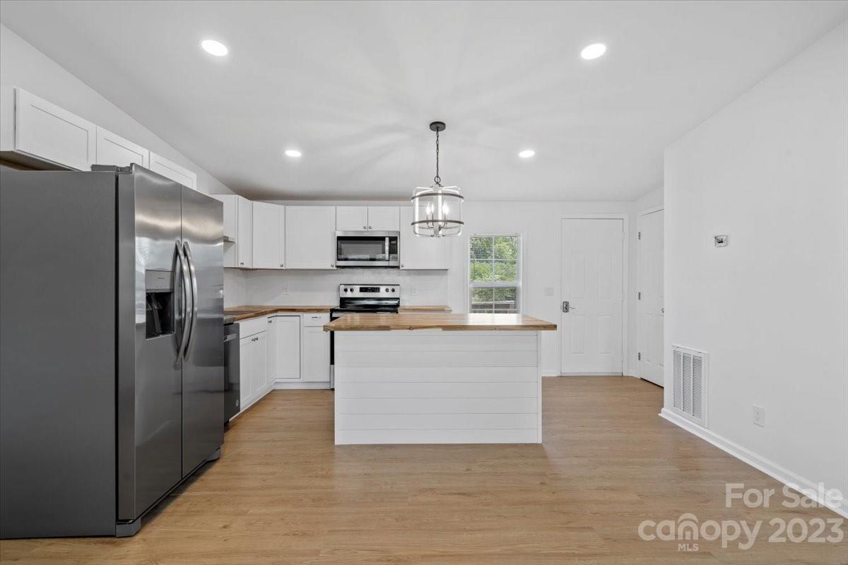 1724 Ruben Road Monroe, NC 28112 - Photo 14 of 28 a large kitchen with white cabinets stainless steel appliances and a chandelier