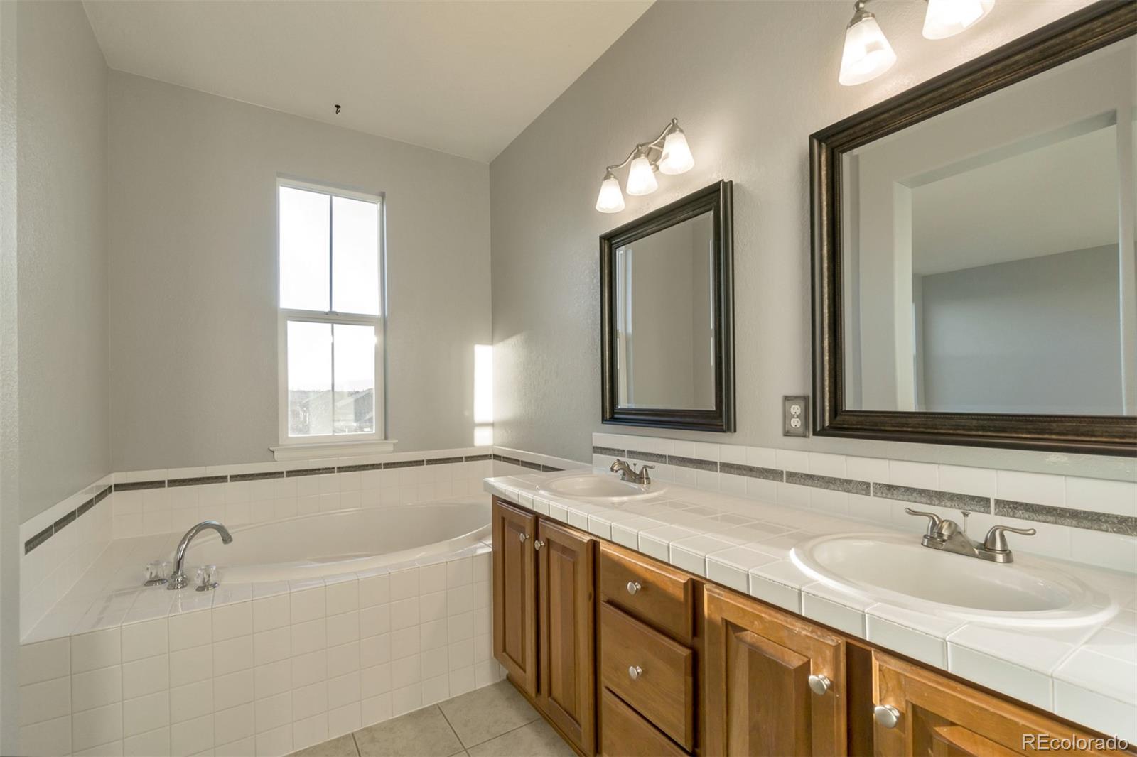 10533 Ashfield Street, Unit D Highlands Ranch, CO 80126 - Photo 16 of 25 a bathroom with a bathtub a double vanity sink and mirror