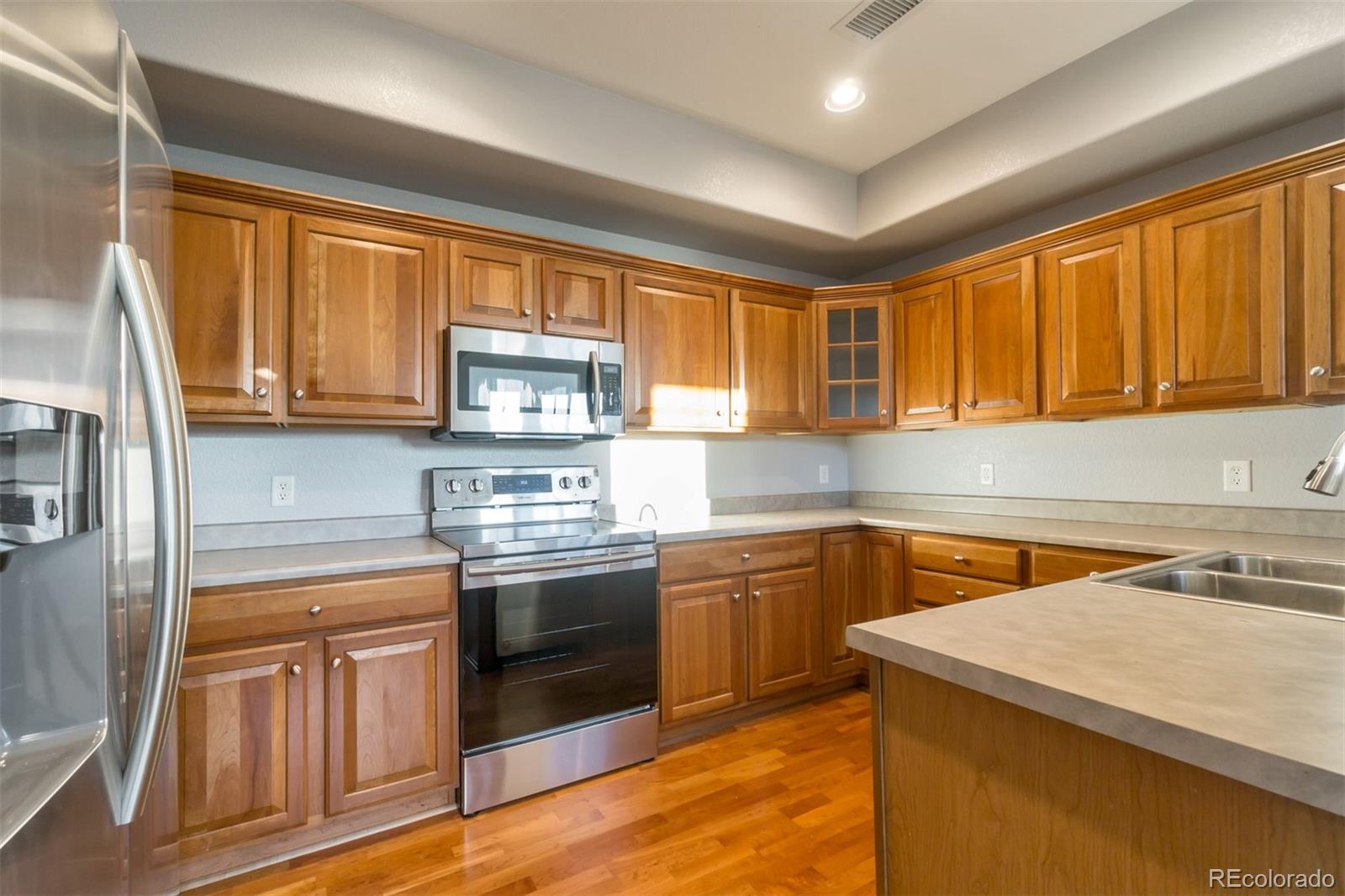 10533 Ashfield Street, Unit D Highlands Ranch, CO 80126 - Photo 7 of 25 a kitchen with stainless steel appliances granite countertop wooden cabinets and a stove top oven