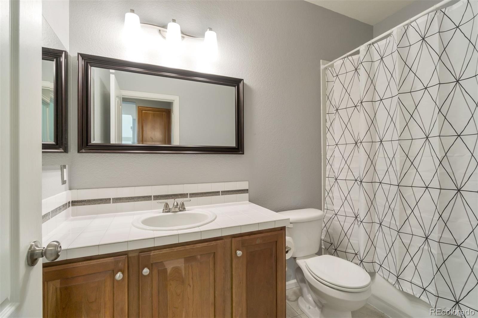 10533 Ashfield Street, Unit D Highlands Ranch, CO 80126 - Photo 9 of 25 a bathroom with a granite countertop toilet sink and mirror