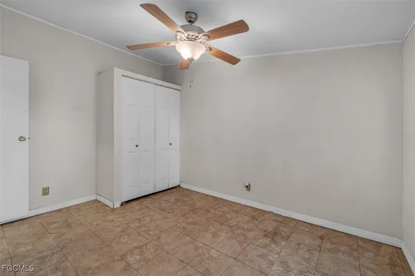 an empty room with a fan & a ceiling fan