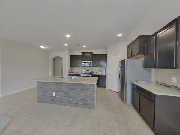 a large kitchen with stainless steel appliances kitchen island granite countertop a refrigerator a sink a stove and a cabinets